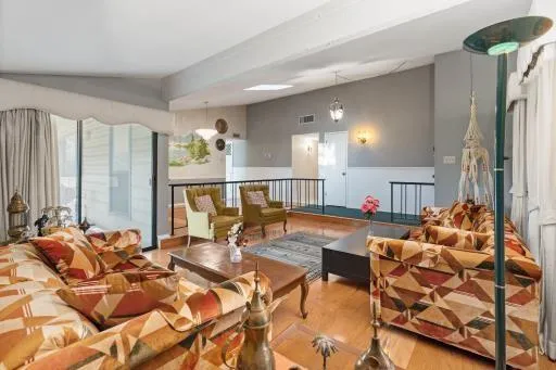 a living room with furniture and a large mirror next to a window