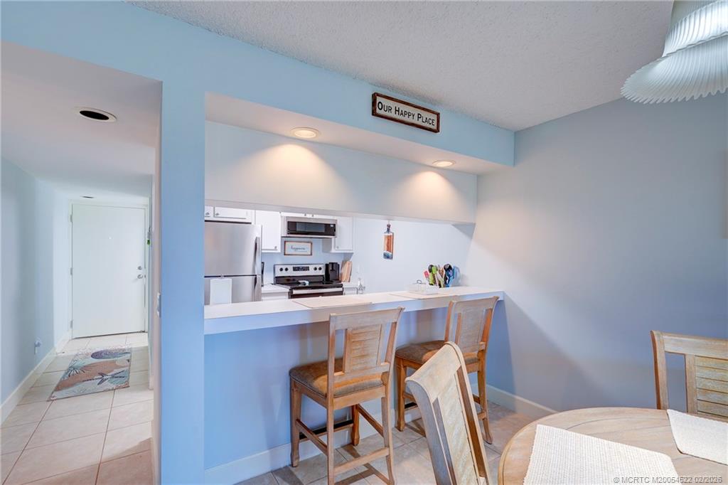 40 Northeast Plantation Road, Unit 309 Jensen Beach, FL 34957 - Photo 17 of 44 a kitchen with stainless steel appliances a sink a stove a refrigerator a microwave with a dining table and chairs