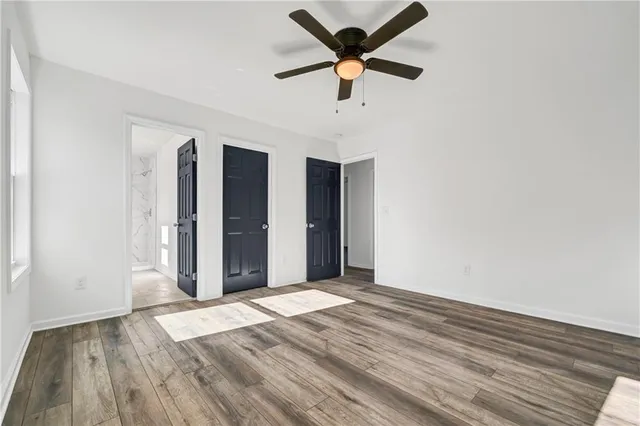 an empty room with wooden floor and a ceiling fan