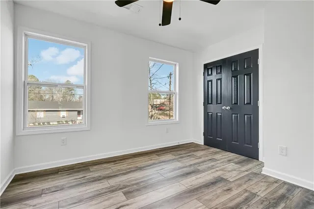 a view of an empty room with a window and wooden floor