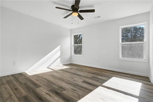 a view of empty room with wooden floor and fan