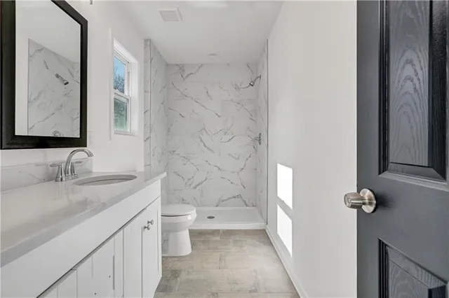 a bathroom with a granite countertop sink toilet and shower