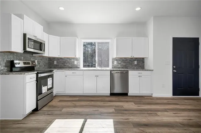a kitchen with stainless steel appliances granite countertop a stove a sink and a microwave