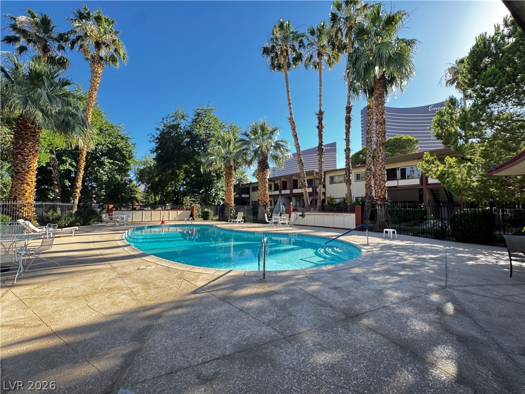 350 East Desert Inn Road, Unit C103 Las Vegas, NV 89109 - Photo 4 of 23 A refreshing pool awaits, surrounded by mature palm trees and ample space for relaxation.
