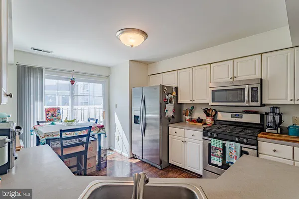 a kitchen with stainless steel appliances kitchen island granite countertop a stove refrigerator and cabinets