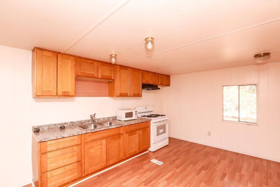 16947 Spring Creek Road Redding, CA 96003 - Photo 6 of 22 a kitchen with stainless steel appliances granite countertop a sink cabinets and wooden floor