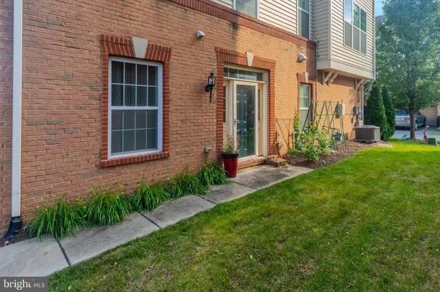 a view of a brick house with a yard and plants