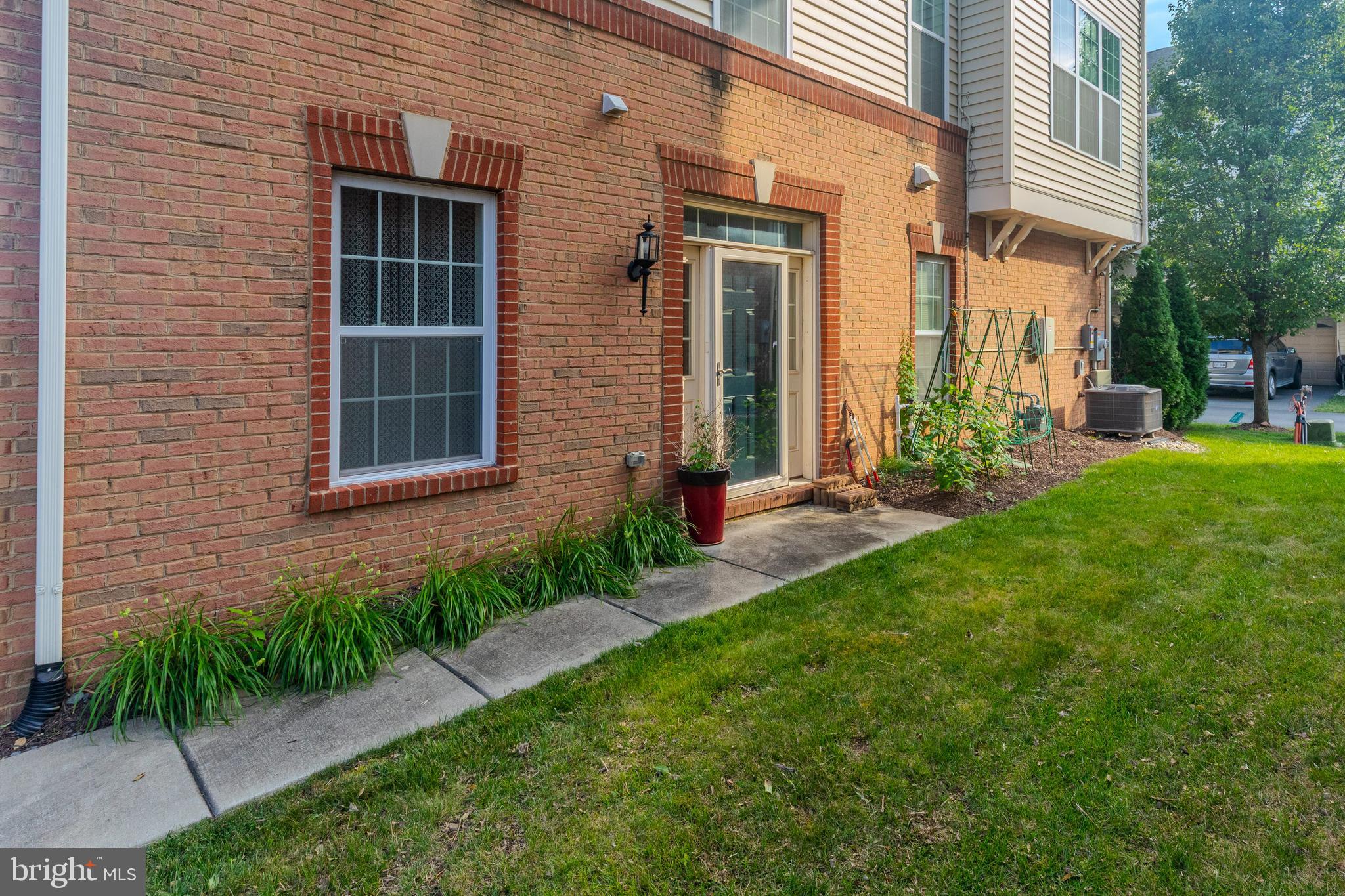 22551 Cambridgeport Square Ashburn, VA 20148 - Photo 1 of 49 a view of a brick house with a yard and plants