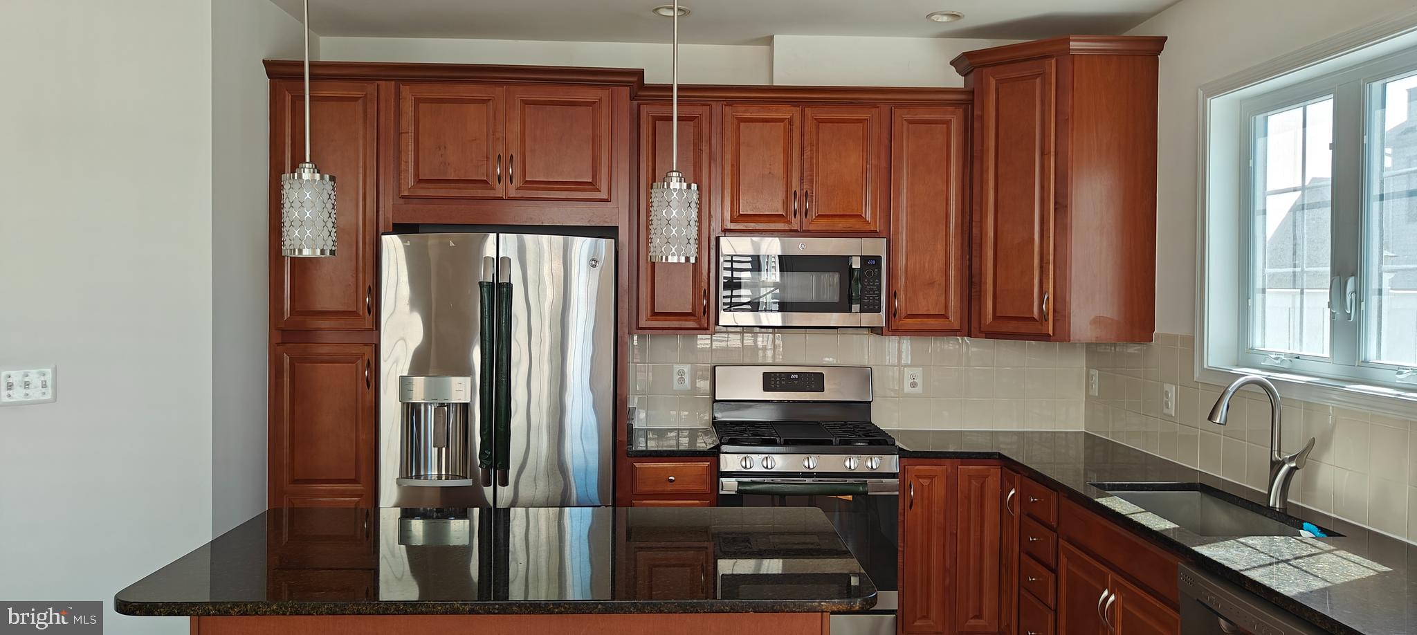 22551 Cambridgeport Square Ashburn, VA 20148 - Photo 2 of 49 a kitchen with kitchen island granite countertop wooden cabinets a sink and stainless steel appliances