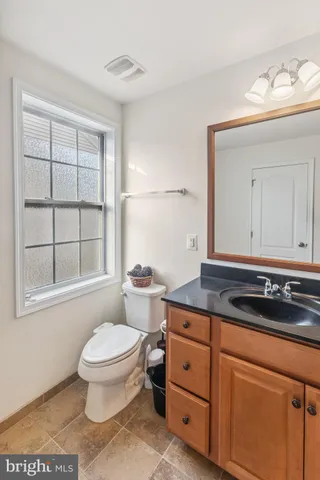 a bathroom with a granite countertop toilet sink and mirror