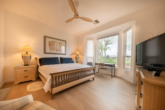 a spacious bedroom with a bed and a flat screen tv