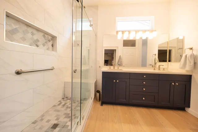 a bathroom with a double vanity sink a mirror and a shower
