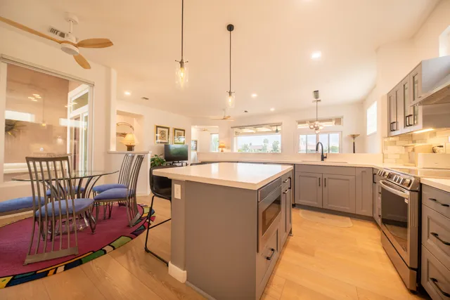 a kitchen with a sink a counter top space stainless steel appliances and a chandelier