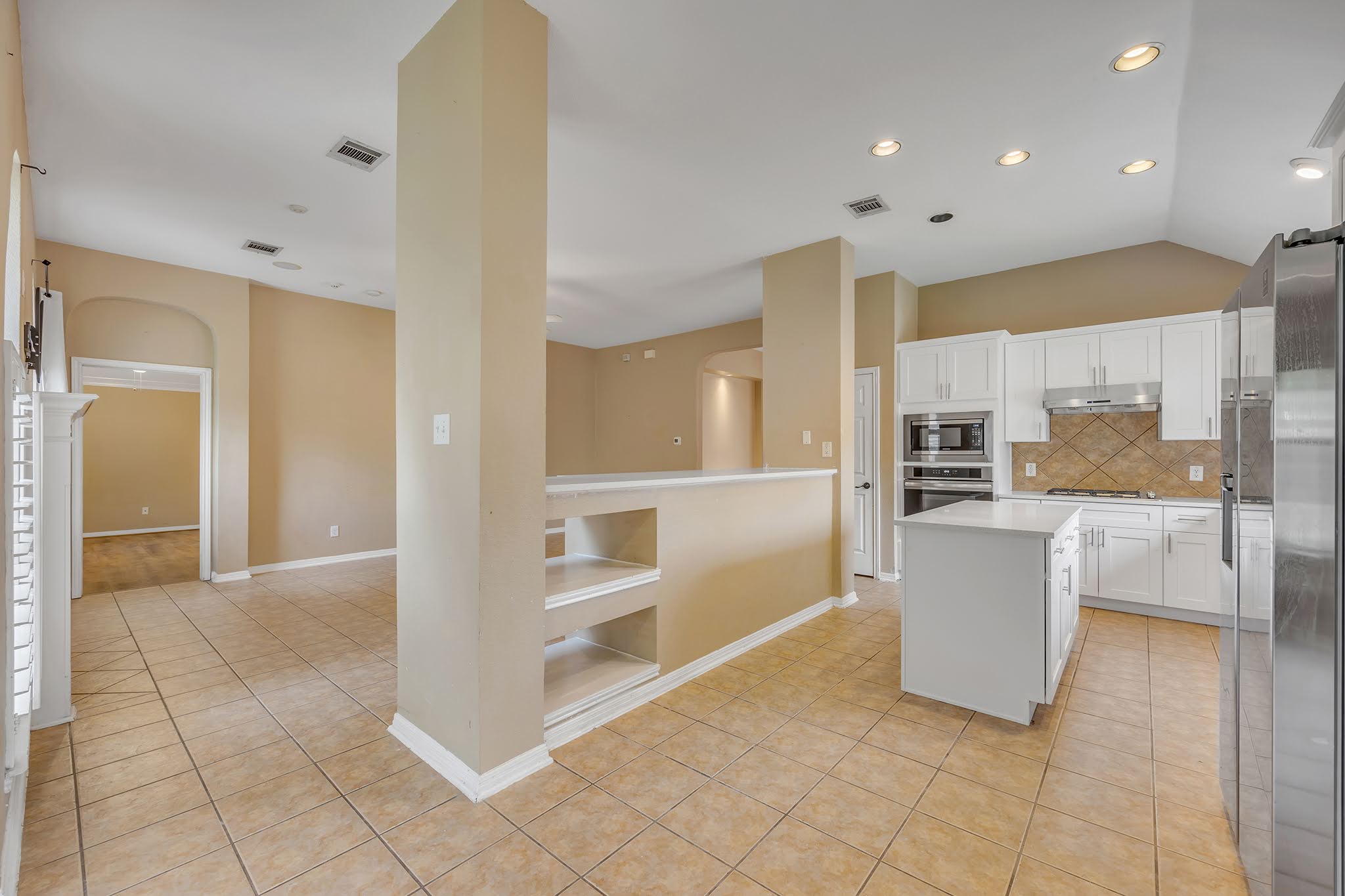 2726 Grimes Ranch Road Austin, TX 78732 - Photo 19 of 35 Kitchen with a kitchen island, white cabinets, light tile patterned floors, tasteful backsplash, and recessed lighting