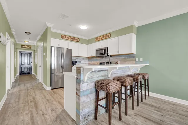 a kitchen with stainless steel appliances a table chairs refrigerator and a sink