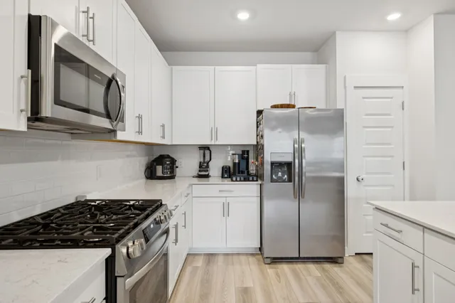 a kitchen with stainless steel appliances granite countertop a stove a refrigerator and a microwave