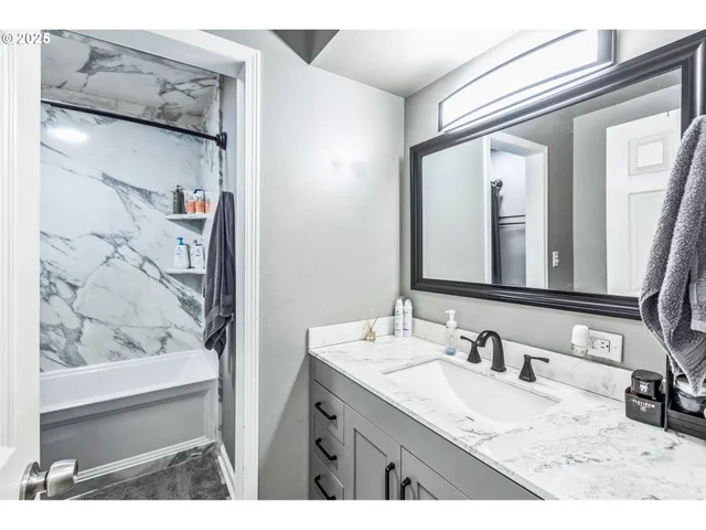 a bathroom with a granite countertop sink a mirror and shower