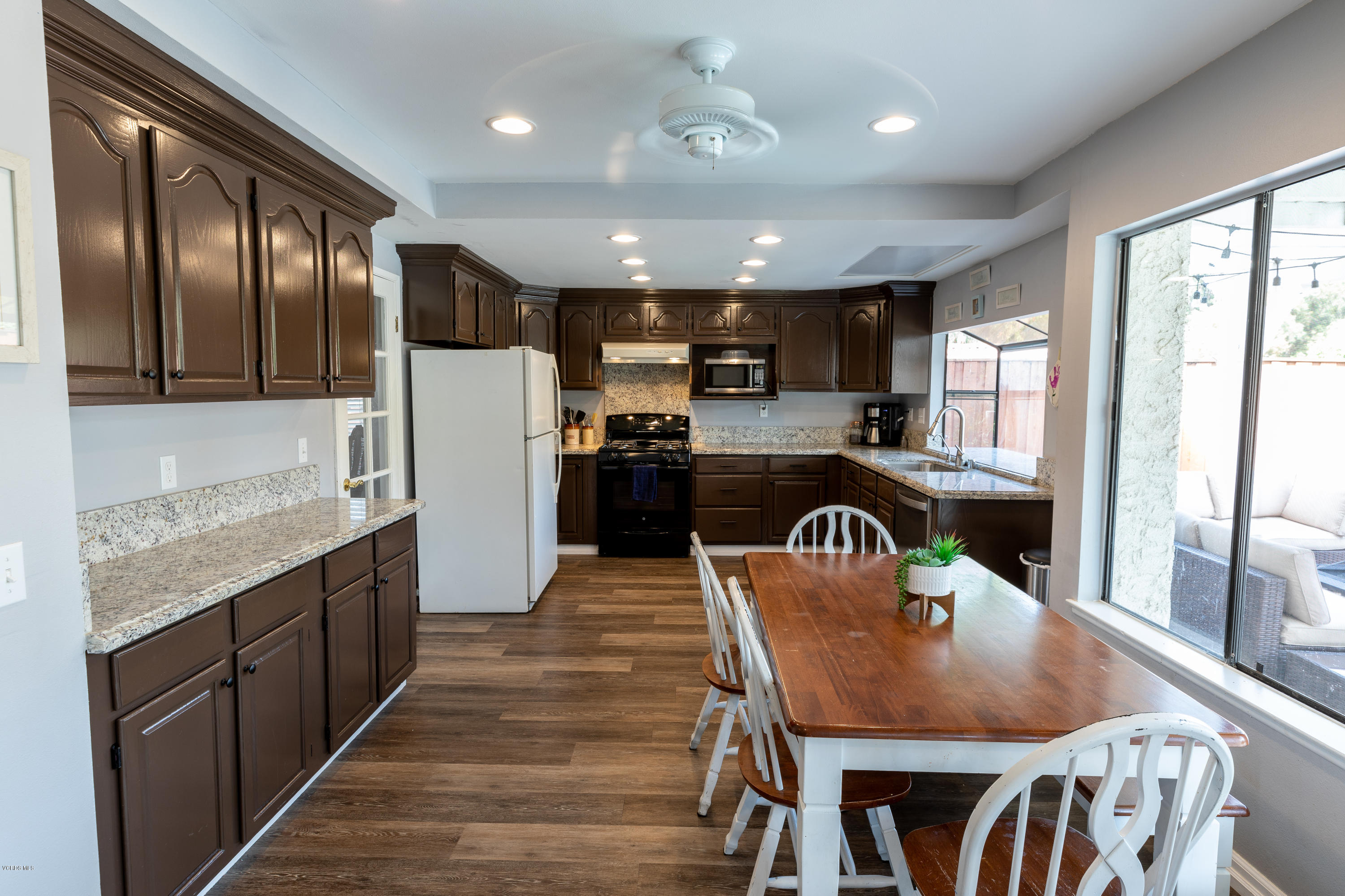 13635 Gunsmoke Road Moorpark, CA 93021 - Photo 12 of 34 a kitchen with stainless steel appliances granite countertop a table chairs sink refrigerator and cabinets