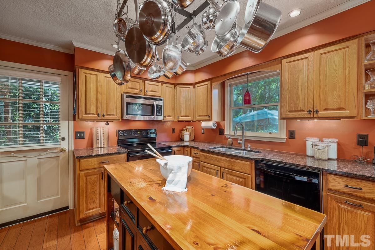 7320 Old Hundred Road Raleigh, NC 27613 - Photo 11 of 39 a kitchen with stainless steel appliances granite countertop a sink a stove top oven a chimney cabinets and a dining table
