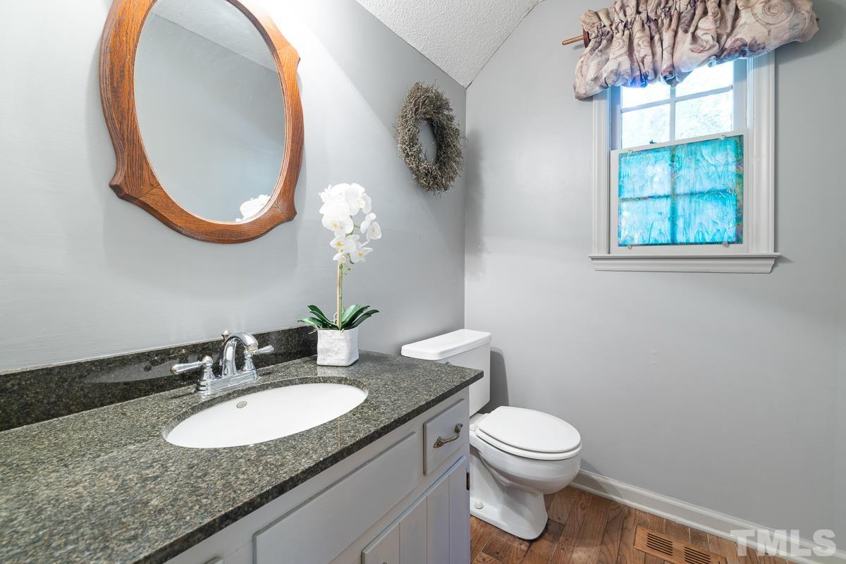 7320 Old Hundred Road Raleigh, NC 27613 - Photo 6 of 39 a bathroom with a granite countertop toilet a sink and a mirror