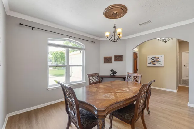 a dining room with wooden floor a chandelier a wooden table and chairs