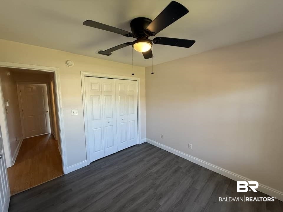 10428 South Side Loop Fairhope, AL 36532 - Photo 23 of 28 Unfurnished bedroom featuring a closet, dark wood-style flooring, ceiling fan, and baseboards