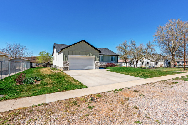 75 North 100th Street West Fillmore, UT 84631 - Photo 59 of 62 Ranch-style house featuring board and batten siding, driveway, an attached garage, and a residential view