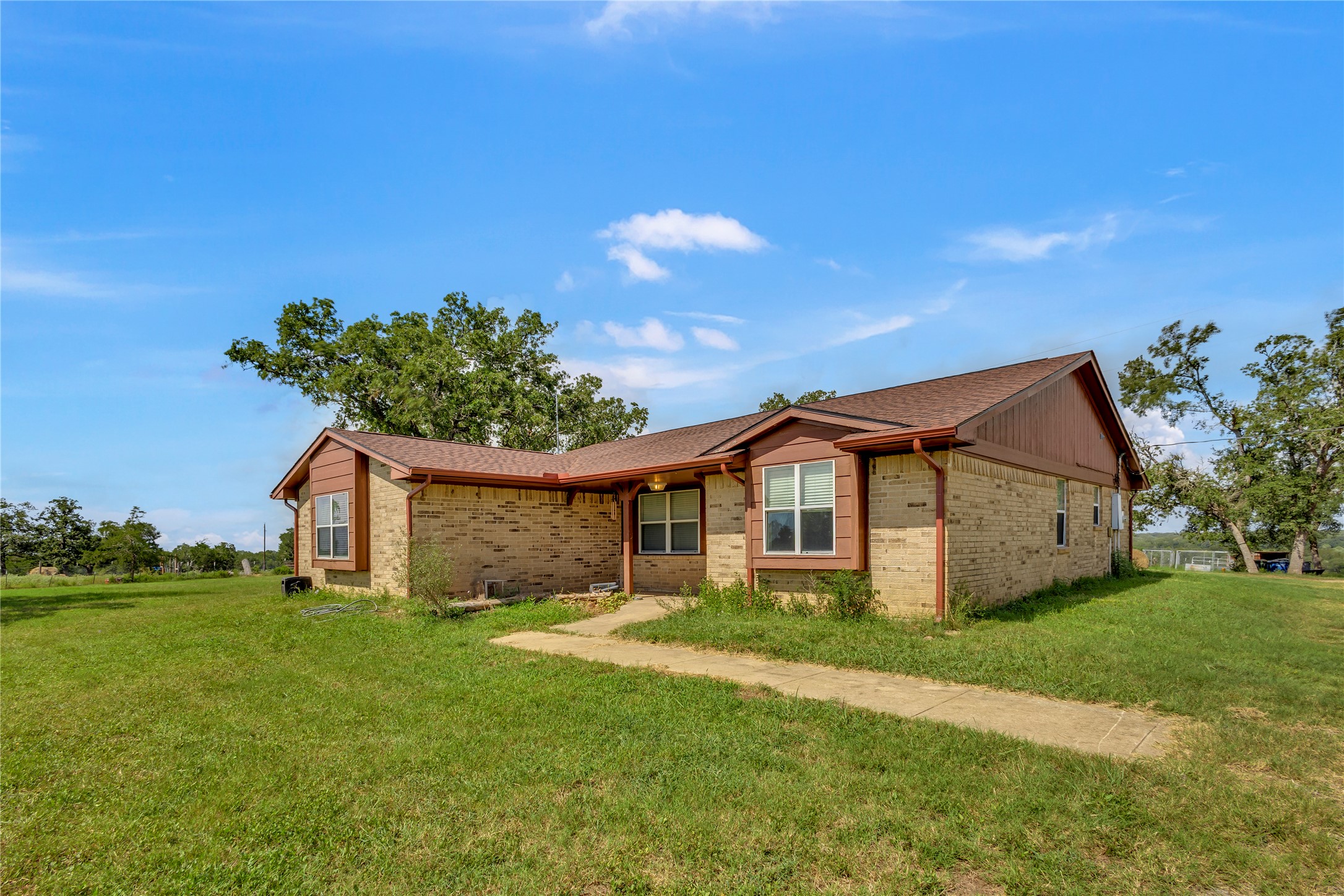 1080 League Line Road Paige, TX 78659 - Photo 37 of 39 A classic brick exterior stands set back on a generous green lawn under blue skies.