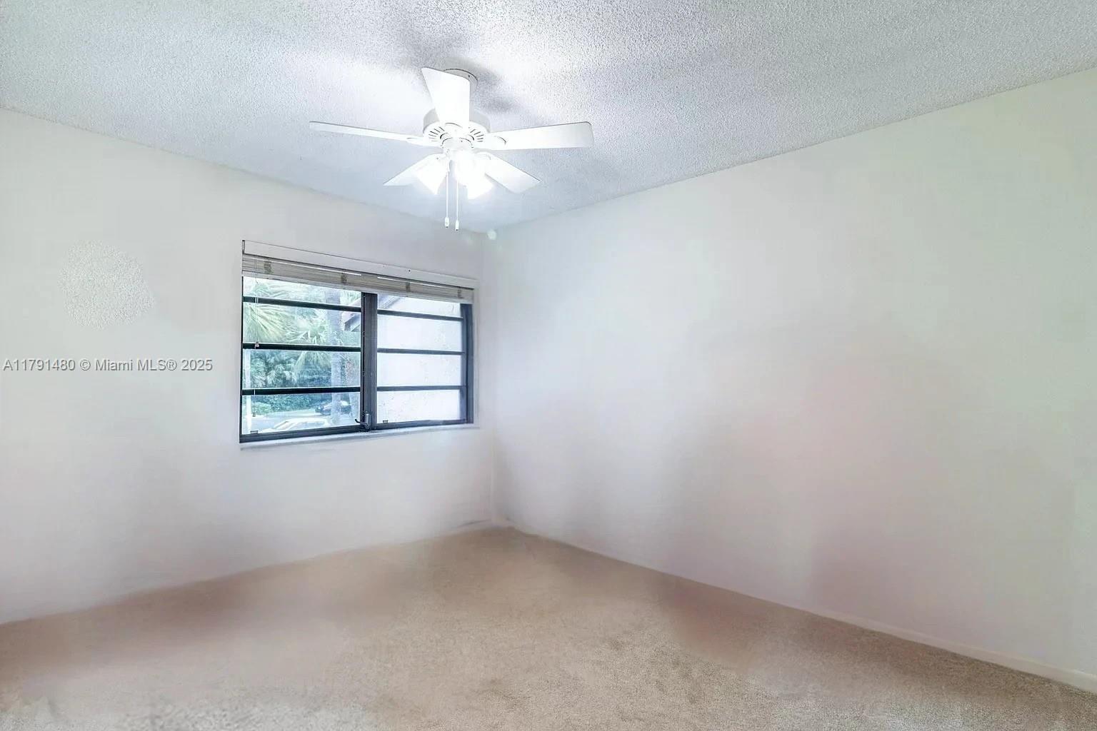 21338 Juego Circle, Unit 11C Boca Raton, FL 33433 - Photo 15 of 17 en empty room with windows and chandelier fan