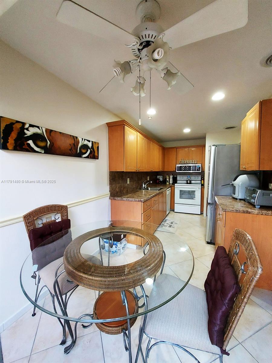 21338 Juego Circle, Unit 11C Boca Raton, FL 33433 - Photo 8 of 17 a kitchen with stainless steel appliances kitchen island granite countertop a sink a stove a dining table and chairs with wooden floor