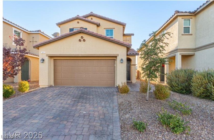 Mediterranean / spanish-style house featuring a tiled roof, stucco siding, decorative driveway, and an attached garage