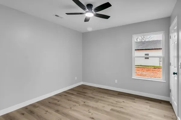 an empty room with wooden floor and windows