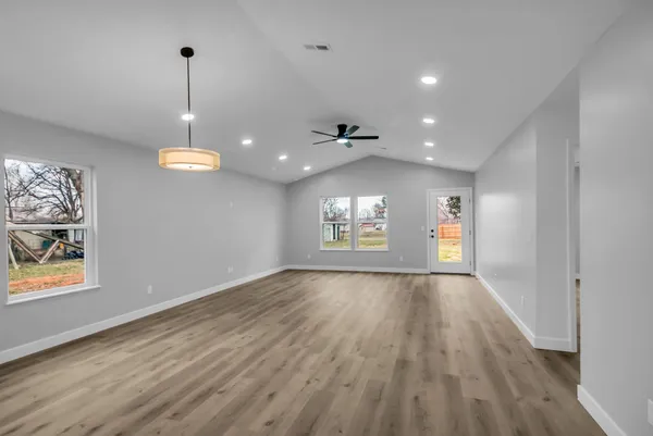 a view of an empty room with a window and wooden floor