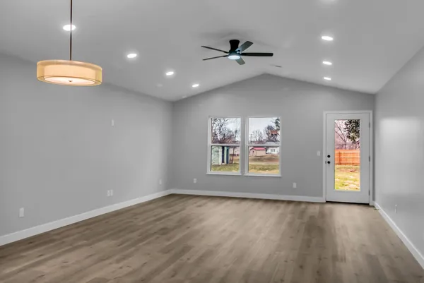 an empty room with windows and ceiling fan