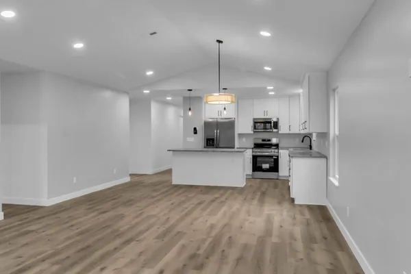 a large kitchen with kitchen island a stove a sink a center island and wooden floor