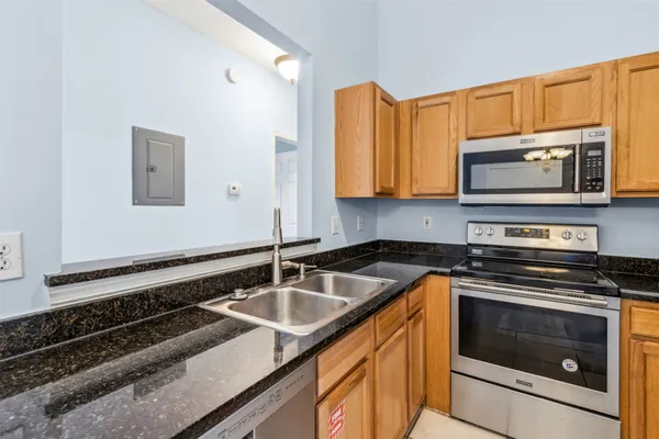a kitchen with granite countertop a stove sink and microwave