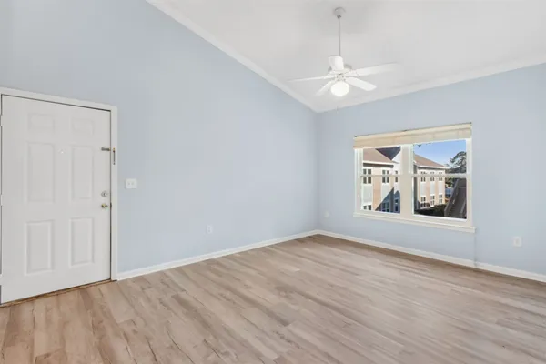 a view of empty room with wooden floor and fan
