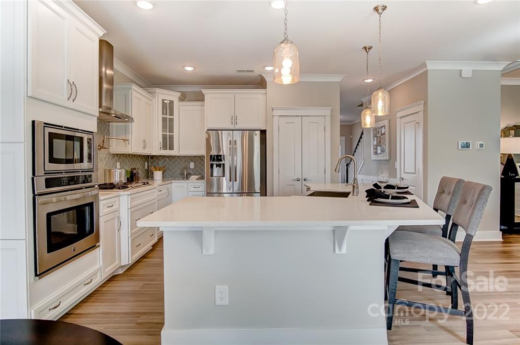 1006 Baldwin Drive Lancaster, SC 29720 - Photo 17 of 48 a kitchen with stainless steel appliances granite countertop a stove top oven a refrigerator a kitchen island a dining table and chairs with wooden floor