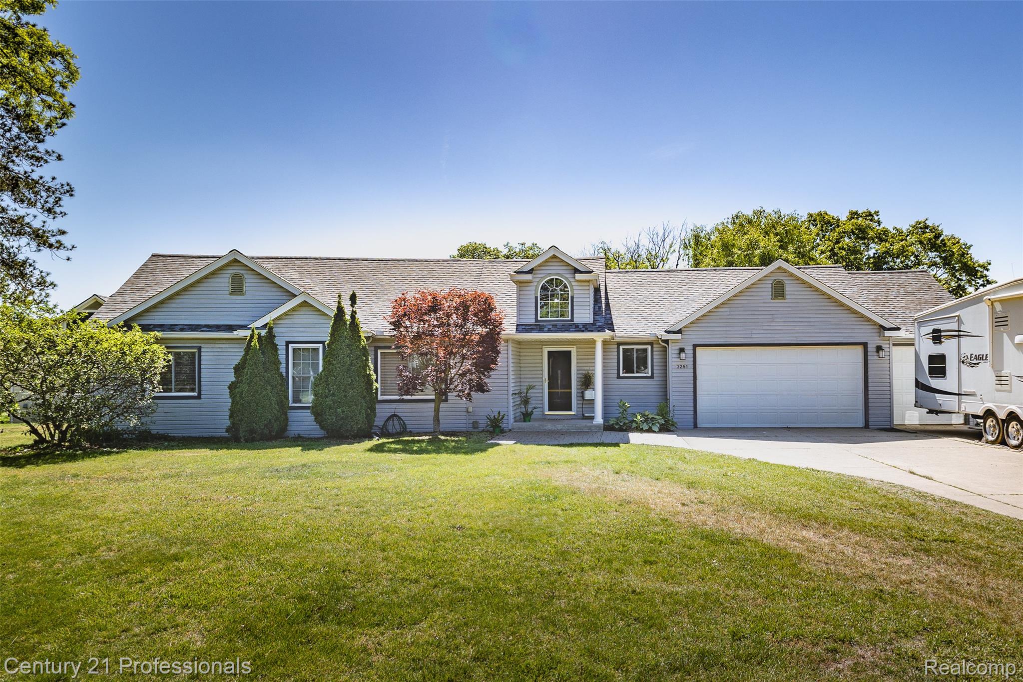 3251 Mann Road Clarkston, MI 48346 - Photo 1 of 40 Light blue siding exterior featuring a prominent two-car garage, established front yard landscaping, an arched window dormer, and a covered front entry