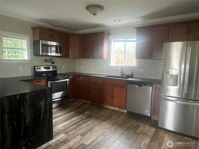 a kitchen with granite countertop stainless steel appliances a sink cabinets and a window