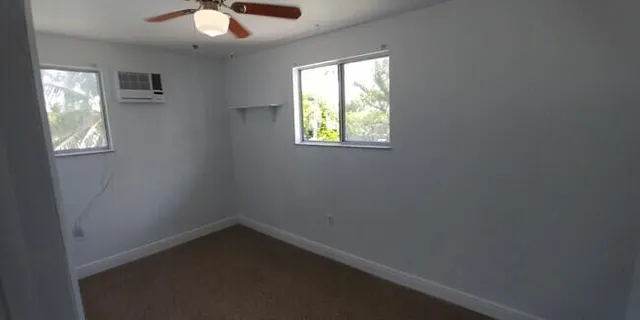 an empty room with windows and fan