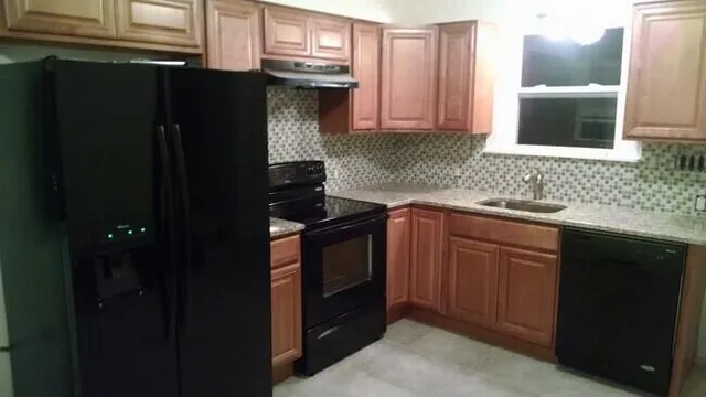 a kitchen with granite countertop a refrigerator and a sink
