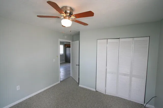 an empty room with closet and a chandelier fan