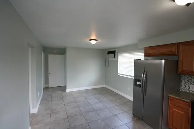 a view of a refrigerator in kitchen and an empty room