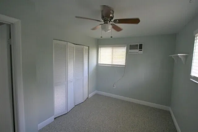 an empty room with a window and a fan