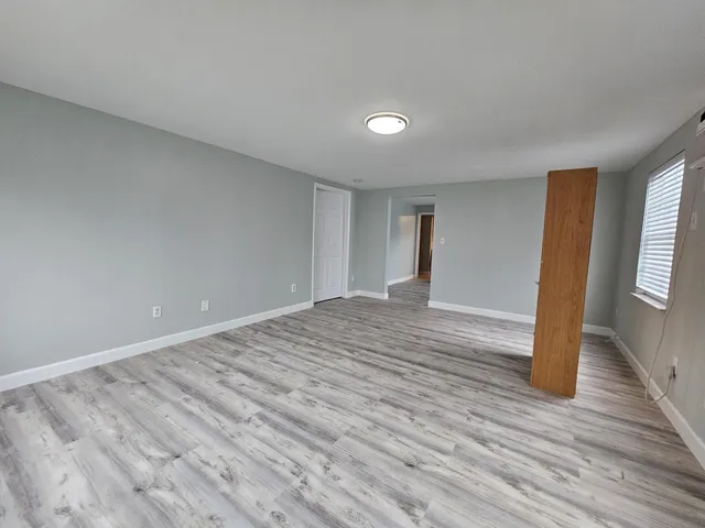 a view of empty room with wooden floor and window