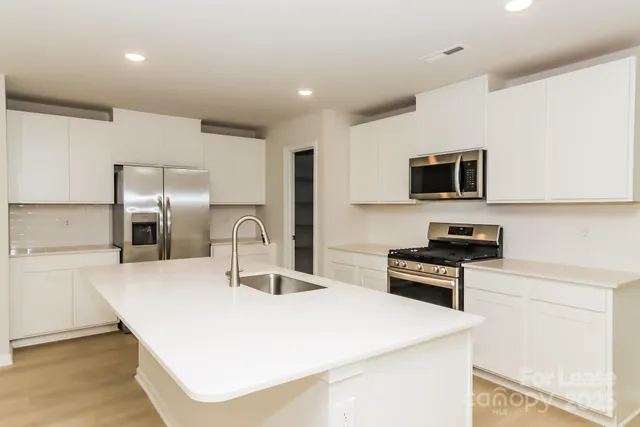 a kitchen with stainless steel appliances a stove a sink and a refrigerator