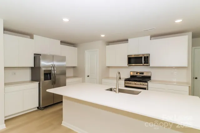 a kitchen with granite countertop a refrigerator stove and sink