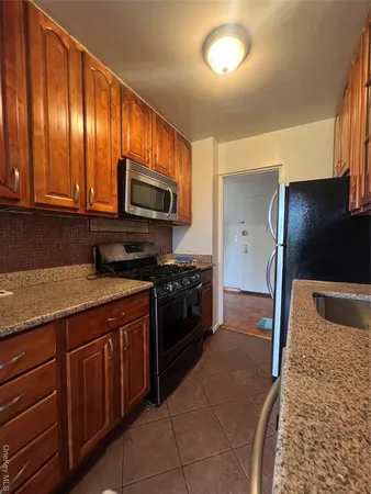 a kitchen with granite countertop wooden cabinets a stove top oven and stainless steel appliances