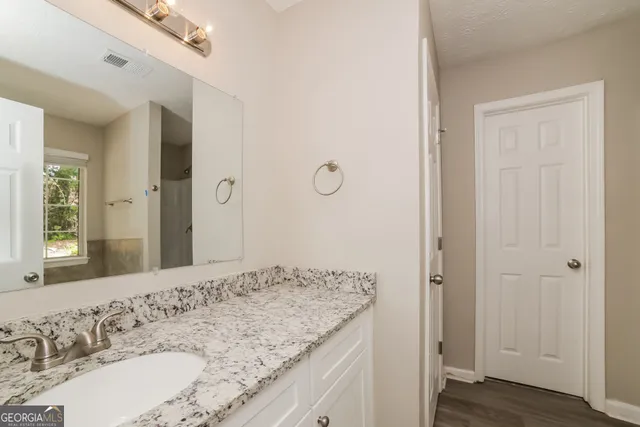 a bathroom with a granite countertop sink and a mirror